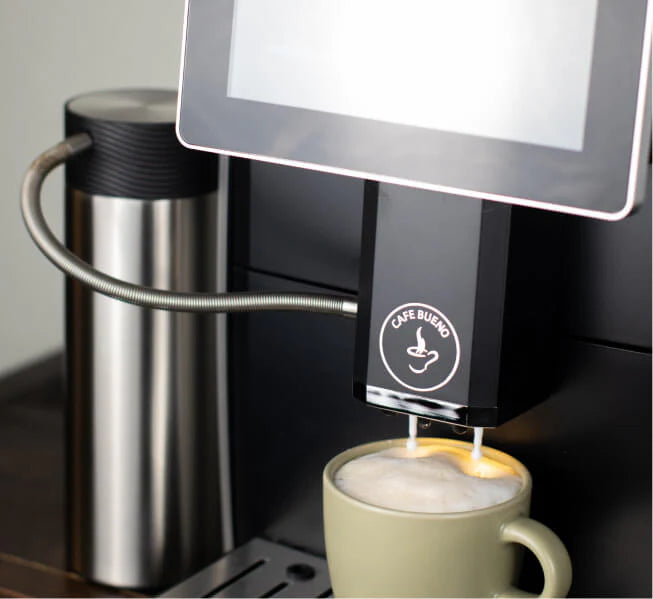 Cafe Bueno super automatic espresso machine automatic milk frother dispensing steamed milk into a sage green ceramic mug, stainless steel milk canister connected via flexible hose, Cafe Bueno logo visible on milk system unit, touchscreen display in background.